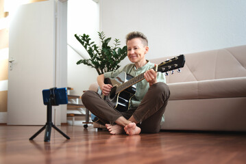 A person learns to play the guitar at home