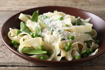 Delicious pasta with green peas and cheese on wooden table