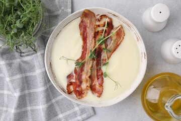 Delicious potato soup with bacon, microgreens and oil on grey table, top view
