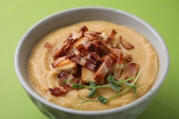 Delicious lentil soup with bacon and croutons on green background, closeup