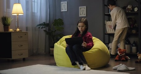 Children watching educational video webinar on digital tablet in the evening at home. Little kids girl and boy looking at tablet screen, watching cartoon or movie, enjoy social media content - Powered by Adobe