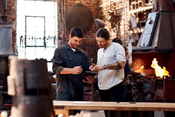 Men, blacksmith and tablet in workshop on teamwork for research and collaboration. Small business,...