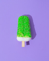 Green glazed ice cream popsicle on light purple background. Minimal summer concept. Ice cream aesthetic. Flat lay.