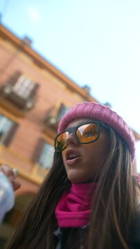 A pretty young lady tours an Italian city, enjoying an audio guide in her headphones.