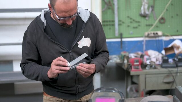 A blacksmith reflects on the creation of a job: he analyzes a metal bar by measuring it with an instrument, evaluating the possible solutions. Solution thinking concept.