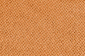 Plain orange velor upholstery fabric, jacquard with fine diamond texture background. Close up, macro cloth textile surface. Wallpaper, backdrop with copy space