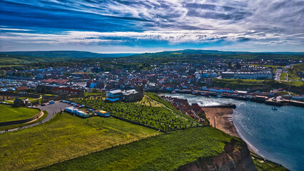 Aerial view of coastal town with harbor and green fields in Whitby, North Yorkshire