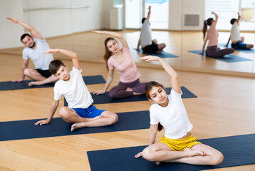Teen girl and boy exercising with mother and father at yoga class, family practicing self-care