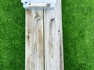 Edge of a teacher or coach's clipboard on top of a wooden sports bench. Green turf sports field background.