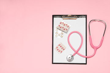 Stethoscope, clipboard and pills on pink background, top view. Space for text