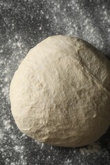 Raw homemade dough and flour on black table, top view