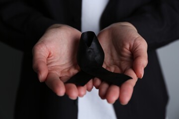 Woman holding black awareness ribbon, closeup view