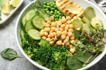 Healthy meal. Tasty vegetables and chickpeas in bowl on grey table, closeup