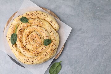 Delicious puff pastry with spinach on grey table, top view. Space for text