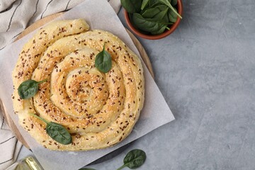 Delicious puff pastry with spinach on grey table, flat lay. Space for text