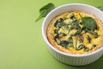Delicious pie with spinach on green background, closeup. Space for text