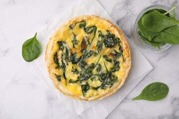 Delicious pie with spinach on white marble table, flat lay
