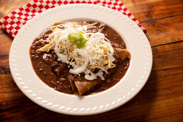 Enfrijoladas. Corn tortillas dipped in bean sauce, covered with cream and cheese, they can be covered or filled with chicken meat, cheese or some other ingredient. Traditional Mexican dish.