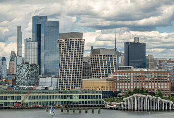 Fototapeta premium New York, NY, USA - August 1, 2023: Urban facade wall over Pier 57 and Little Island Amphitheater under blue cloudscape.