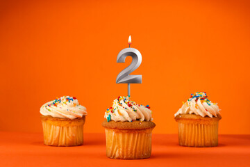 Candle number 2 - Celebration with birthday cupcake on orange background