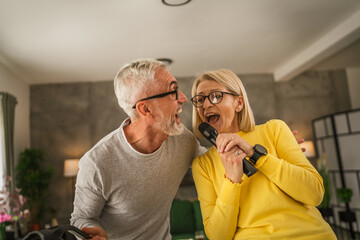 Mature wife and husband hold microphone and sing together karaoke