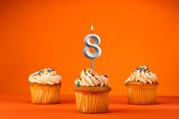 Candle number 8 - Celebration with birthday cupcake on orange background