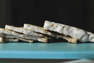 Raw Tempeh or Tempeh. Tempeh slices on a cutting board. Tempeh is made from fermented soybeans.