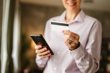 Close up of hands hold credit card and mobile phone buy online home
