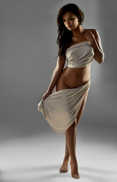 Woman, body and nude on studio background with fabric for covering with art deco in confidence. Slim, toned and healthy person covered with sarong, seductive and goddess with elegance in Spain