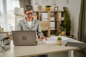 One mature caucasian businesswoman work on laptop at office