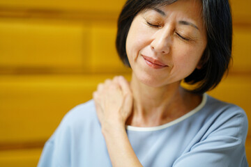 肩を揉む中年女性　疲れイメージ