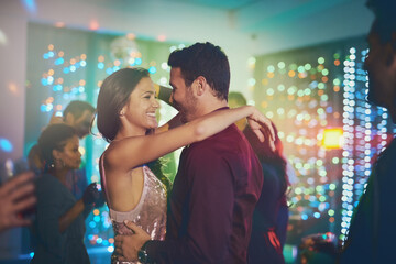 Couple, hug and dance in club at night on date with love in marriage or relationship. People, celebrate and embrace together with happiness at neon disco, party or rave at techno music festival