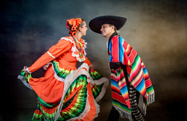 Latin Mexican couple with Jalisco, charro costumes A man and woman in traditional Mexican clothing dance together