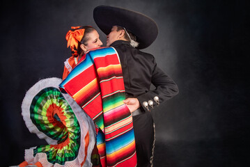 Latin Mexican couple with Jalisco, charro costumes A man and woman in traditional Mexican clothing are embracing each other