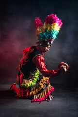 Matlachines Dancer from Coahuila Mexico A man in a colorful costume is kneeling on the ground