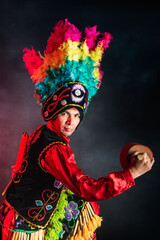 Fototapeta premium Matlachines Dancer from Coahuila Mexico A man wearing a colorful headdress and a red shirt is holding a drum