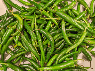 A vibrant pile of large green chilies catches the eye with their glossy, smooth surfaces and rich, deep hues.