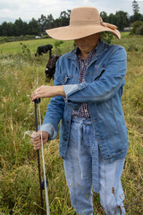 An adult Latina woman adjusting the electric fence for cattle in an open field, concept of livestock farming