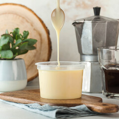 Condensed milk pouring from a spoon, perfect for desserts and sweetening beverages.