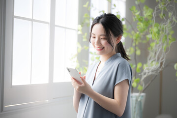 窓際でスマホを見る女性