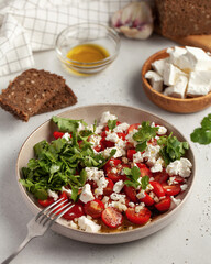 Fresh tomato and feta cheese salad garnished with cilantro and drizzled with olive oil