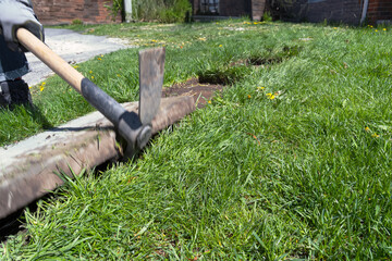 A man is using a shovel to dig a hole in the grass