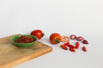 Portrait of tomato chili sauce in a green bowl isolated on a white background, seasoned with tomatoes, chilies, shallots, garlic.