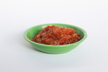Portrait of tomato chili sauce in a green bowl isolated on a white background.