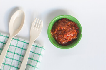 Portrait of tomato chili sauce in a green bowl isolated on a white background.