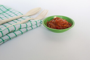 Portrait of tomato chili sauce in a green bowl isolated on a white background.