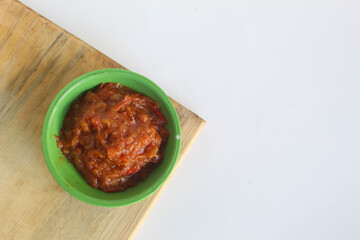 Portrait of tomato chili sauce in a green bowl isolated on a white background.