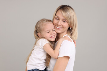 Family portrait of happy mother and daughter on grey background