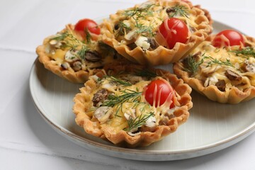 Tasty tartlets with cheese, tomatoes, mushrooms and dill on white table, closeup