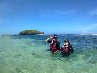 indonesian young couple swimming snorkeling enjoying holiday at the beach